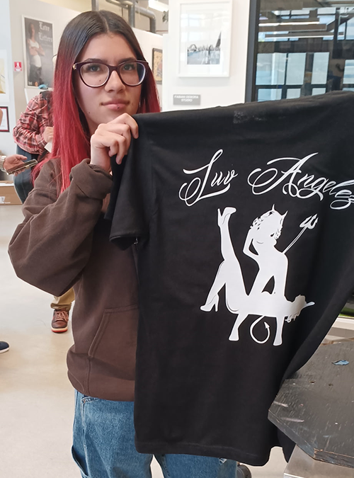 Boyle Heights YouthSource intern Gizelle Lopez showing off her Luv Angelez business logo on a freshly silk-screened t-shirt